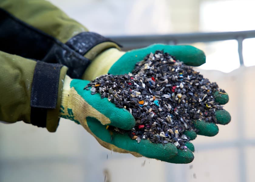 Work gloves holding plastic regrind for reprocessing